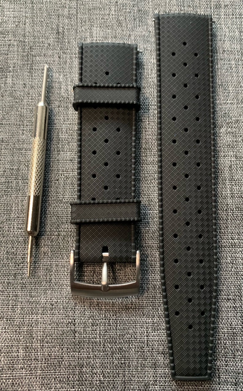 Puede incluir: Una correa de reloj de caucho negro con un patr&oacute;n texturizado y una hebilla plateada. La correa est&aacute; dise&ntilde;ada para un reloj con una anchura de leng&uuml;eta de 20 mm.