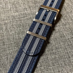 May include: A dark blue and silver striped watch strap with a silver buckle.