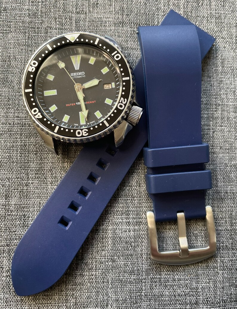 Puede incluir: Un reloj de buceo autom&aacute;tico Seiko con esfera negra, bisel de acero inoxidable y correa de caucho azul. La esfera del reloj tiene marcadores y agujas luminosas. La correa es de color azul oscuro y tiene una hebilla plateada.