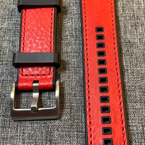 Op de afbeelding: Rood leren horlogeband met zwarte stiksels en een zilveren gesp. Het bandje heeft een gestructureerd oppervlak en is ontworpen voor een smartwatch.