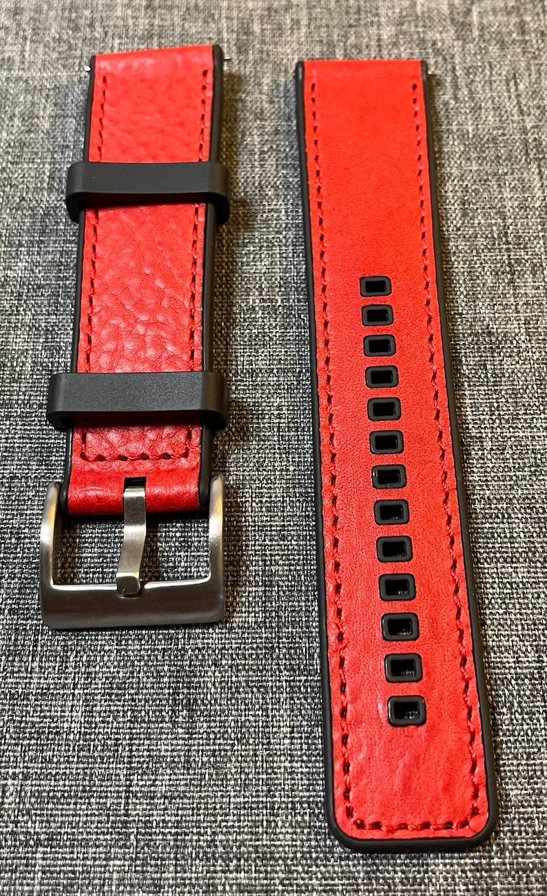 Op de afbeelding: Rood leren horlogeband met zwarte stiksels en een zilveren gesp. Het bandje heeft een gestructureerd oppervlak en is ontworpen voor een smartwatch.