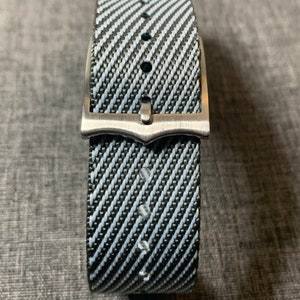 May include: A black and white striped watch strap with a silver buckle.
