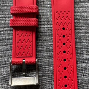 Puede incluir: Correa de reloj roja brillante con hebilla de acero inoxidable. La correa presenta un dise&ntilde;o texturizado con una serie de patrones en zigzag. La correa tiene el texto "22/18 80" y "22/18 120" impreso.