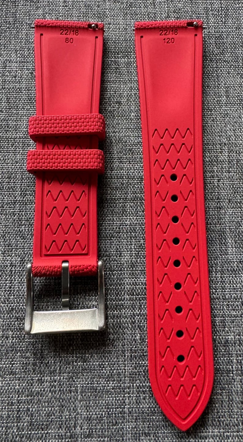 Puede incluir: Correa de reloj roja brillante con hebilla de acero inoxidable. La correa presenta un dise&ntilde;o texturizado con una serie de patrones en zigzag. La correa tiene el texto "22/18 80" y "22/18 120" impreso.