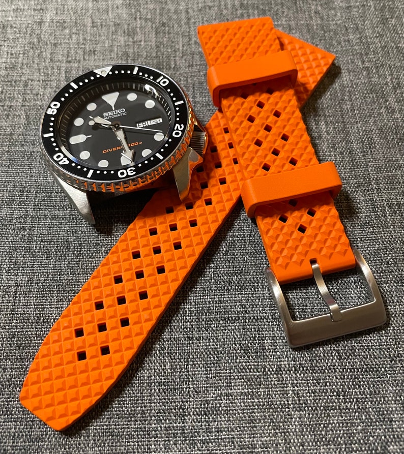Puede incluir: Correa de reloj de caucho naranja con un patr&oacute;n de diamante y una hebilla plateada. La correa est&aacute; dise&ntilde;ada para un reloj con una anchura de leng&uuml;eta de 20 mm.