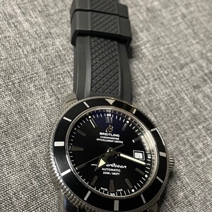 May include: A black Breitling Superocean Automatic 200m/660ft watch with a black rubber strap. The watch face has white markings and a date window.