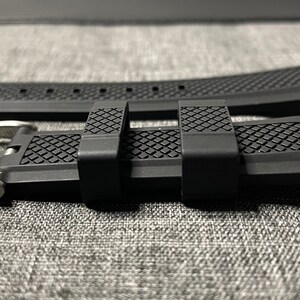 May include: A black rubber watch strap with a silver buckle. The strap has a textured pattern and is designed for a watch with a 22mm lug width.