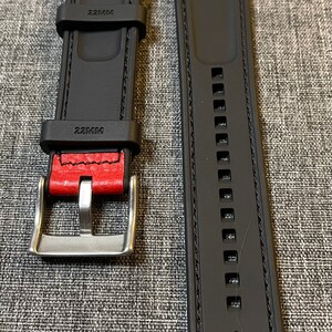Op de afbeelding: Twee zwarte horlogebandjes met rode stiksels en een zilveren gesp. De bandjes zijn 22 mm breed en hebben een getextureerd oppervlak.