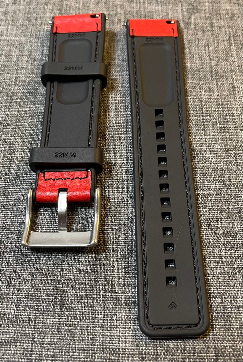 Op de afbeelding: Twee zwarte horlogebandjes met rode stiksels en een zilveren gesp. De bandjes zijn 22 mm breed en hebben een getextureerd oppervlak.