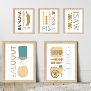 May include: Five framed prints with illustrations and text. The prints are in a light wood frame with a white mat. The prints are hung on a white wall. The prints feature the words "BALUUUT", "SORBETES", "ISAW", "FISH", and "BANANA CUE".