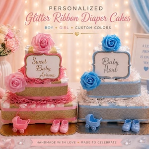 May include: Two tiered nappy cakes decorated with glitter ribbons and artificial roses. The left cake features pink accents and a sign reading Sweet Baby Avanna. The right cake features blue accents and a sign reading Baby Hart. Both include miniature strollers and baby shoes.
