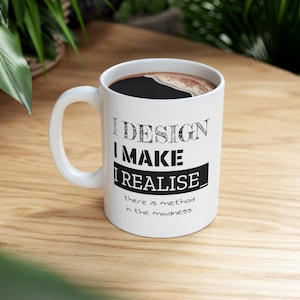 May include: White ceramic coffee mug with black text that reads "I DESIGN I MAKE I REALISE there is method in the madness".