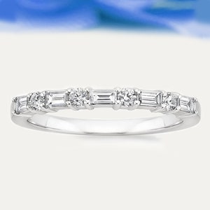 Könnte beinhalten: Ein zarter Ring aus Weißgold mit abwechselnd runden und baguetteförmigen Diamanten. Der Ring zeigt eine Reihe funkelnder Edelsteine, die ein durchgehendes, elegantes Design bilden. Die Diamanten sind eng beieinander gesetzt, was den Glanz des Rings verstärkt.