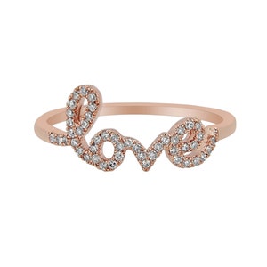 May include: A rose gold ring with the word "LOVE" spelled out in cursive. The letters are outlined with small diamonds.