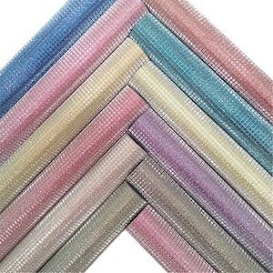 May include: Assortment of sparkly, iridescent ribbon rolls in various colors, including pink, blue, and gold. The ribbon is woven with a grid pattern and has a shimmery finish.