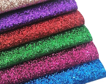 May include: A stack of six rectangular sheets of glitter fabric arranged in a cascading pattern. The colors from top to bottom are rose gold, purple, red, green, magenta, and blue. Each sheet features a dense, uniform layer of reflective glitter.