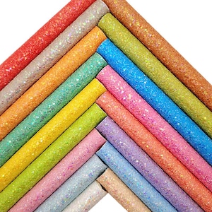 Puede incluir: Una colección de hojas de purpurina de colores dispuestas en forma de cheurón. Las hojas muestran una variedad de colores, incluyendo rojo, naranja, amarillo, verde, azul y rosa, todos con un acabado brillante.