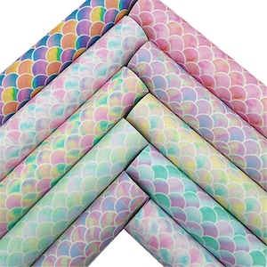 May include: A set of eight iridescent mermaid scale patterned faux leather sheets. The sheets are in shades of pink, blue, green, and yellow. The scales are embossed and have a subtle glitter finish.