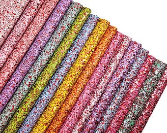 May include: A collection of rectangular sheets of glitter fabric arranged in a diagonal fan pattern. The sheets feature a dense, multi-colored speckled texture with various hues including red, pink, purple, green, yellow, orange, and black.