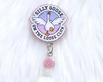 May include: A pink and purple badge holder with a white goose and the text "Silly Goose On The Loose Club".