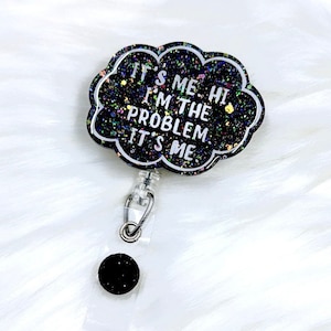 May include: Black glitter badge holder with a black cloud-shaped charm that reads "It's me. Hi. I'm the problem. It's me."