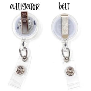 May include: Two clear plastic retractable badge holders with silver clips. The top holder has the word "alligator" printed on it. The bottom holder has the word "belt" printed on it.