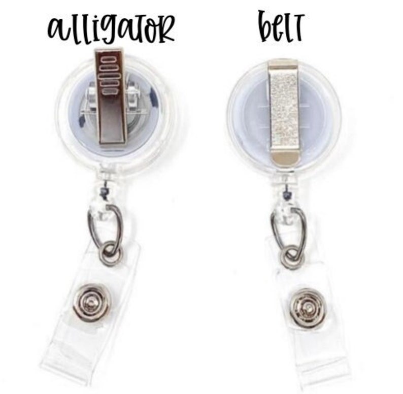 May include: Two clear plastic retractable badge reels with metal hardware. The left reel features an alligator clip labeled 'alligator' above it, and the right reel features a belt clip labeled 'belt' above it. Both have a clear vinyl strap.