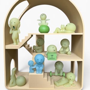 May include: A beige wooden dollhouse with multiple levels, housing various small, stylized figurines in shades of green and blue. Some figurines are posed in different activities, such as lifting weights or reclining. A green box with the word "FRAGILE" is also present.