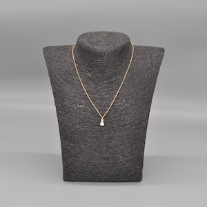 Puede incluir: Un collar de cadena de oro con un pequeño colgante de perla blanca redonda.