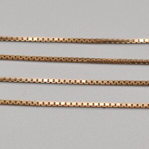May include: Four strands of gold chain, each with a box chain pattern.