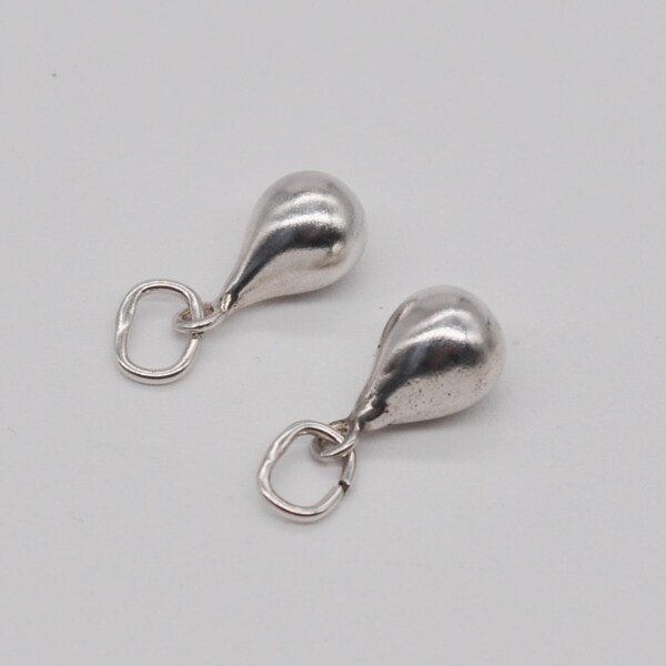 May include: Two silver-colored teardrop-shaped pendants with small, open loop attachments. The pendants have a smooth, reflective surface and are displayed against a plain white background. The jewelry is likely for necklaces or earrings.