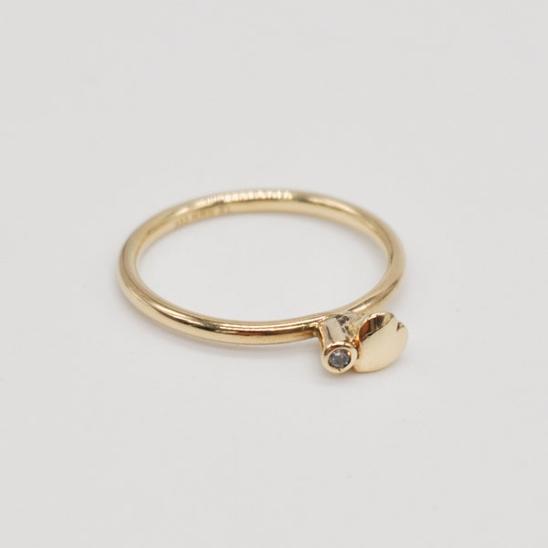 May include: A gold ring with a small diamond and a heart-shaped charm.