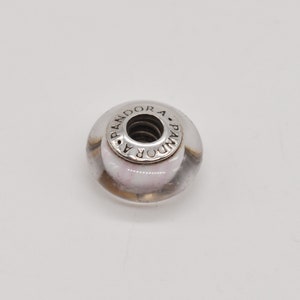 May include: A silver charm bead with a clear glass centre and the word "PANDORA" engraved around the edge.