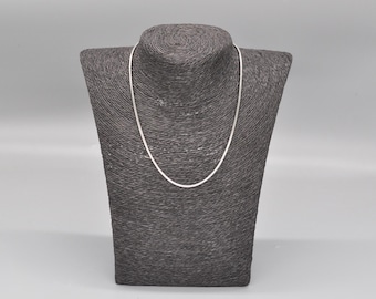 Puede incluir: Un collar de cadena de plata en un maniquí de busto gris.