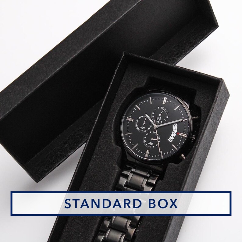May include: A black wristwatch with a black metal band is displayed inside a black box. The watch face has multiple sub-dials and a date display. The box has the words "STANDARD BOX" in a white rectangle.