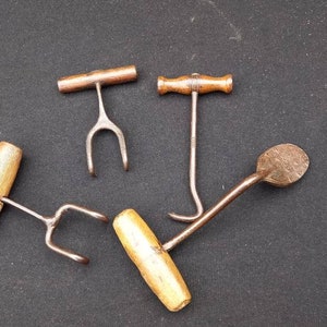 Könnte beinhalten: Vier antike Metallhaken mit Holzgriffen. Die Haken sind in verschiedenen Formen und Größen. Die Griffe sind alle aus Holz und haben eine natürliche Oberfläche.