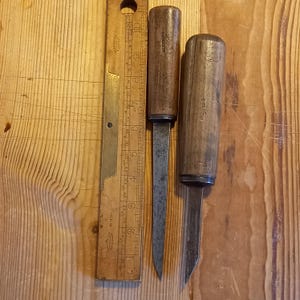 Peut inclure: Deux outils anciens à manche en bois et lames en métal. Les outils mesurent environ 15 cm de long et ont un manche en bois brun foncé. Les lames sont en métal et sont affûtées à pointe. Les outils sont posés sur une surface en bois.