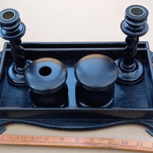 Puede incluir: Conjunto de escritorio de madera negra con dos tinteros y dos candelabros. Los candelabros tienen un diseño retorcido y los tinteros tienen una forma redonda.