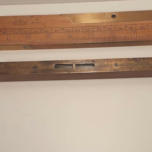 May include: A brass level with a wooden base and a glass bubble level. The level is marked "Stanley" and has a brass screw on each end.