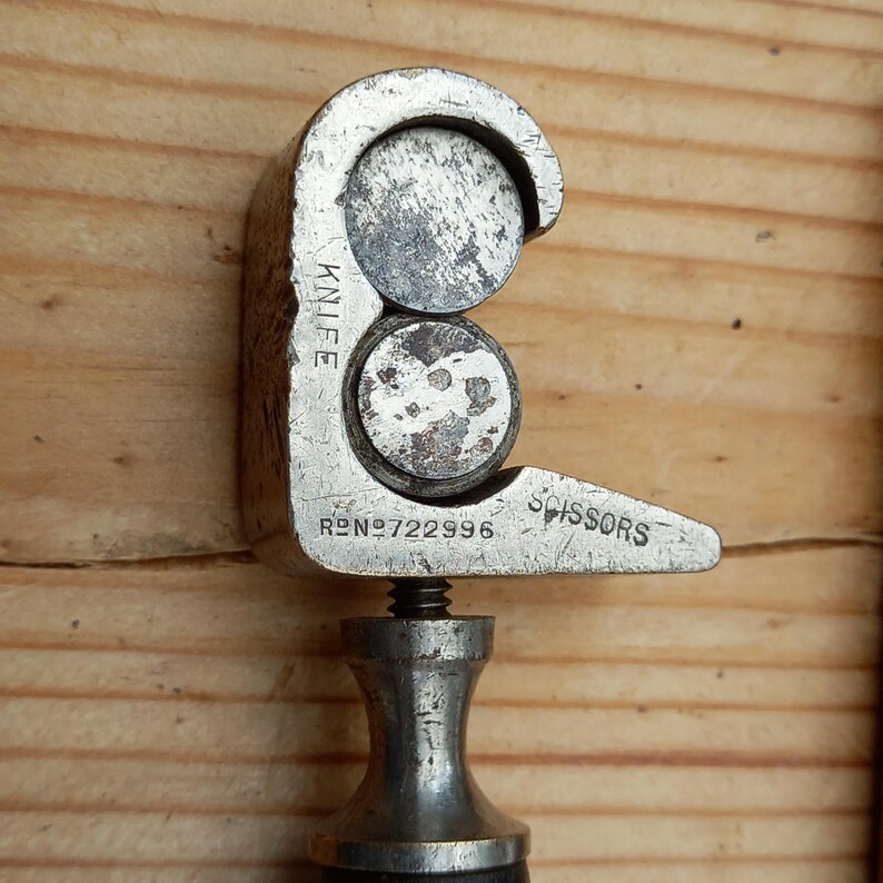 May include: A silver-toned metal tool with a handle and two circular cutting blades. The tool is labeled "KNIFE" and "SCISSORS" and has the number "722996" printed on it.