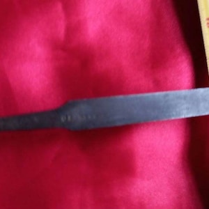 Peut inclure: Un gros plan d'un ciseau en métal avec un manche en laiton. Le ciseau mesure environ 38 cm de long et a une pointe acérée. Le manche est en laiton et a une finition lisse.