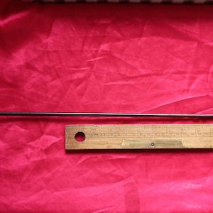 Könnte beinhalten: Ein Werkzeug aus Metall mit Holzgriff und einem langen, dünnen Schaft. Das Werkzeug ist etwa 25 cm lang und hat einen Holzgriff mit der Aufschrift "STAHL". Das Werkzeug liegt auf einer roten Oberfläche neben einem Holzlineal.