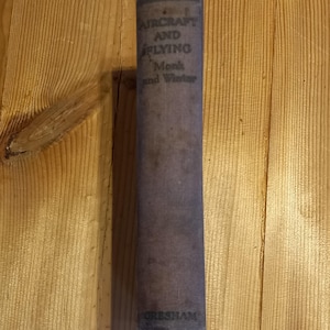 May include: A vintage book titled "Aircraft and Flying" by Monk and Winter. The book is bound in brown paper with a faded, worn look. The book is published by Gresham.