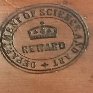 May include: A circular stamp with the text "Department of Science and Art, Reward" and a crown design.