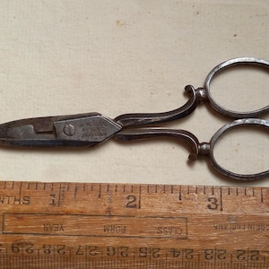 Può includere: Forbici antiche color argento con manici decorati e una lama appuntita. Le forbici sono lunghe circa 7,5 cm e hanno l'iscrizione "ALFRED WILCOX & CO. SHEFFIELD" sulla lama.