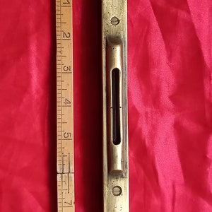 May include: A brass level with a black liquid level vial. The level is about 7 inches long.