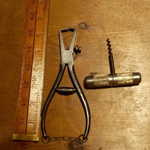 May include: A set of two vintage tools, a silver wire cutter with a chain and a silver corkscrew with a wooden handle.