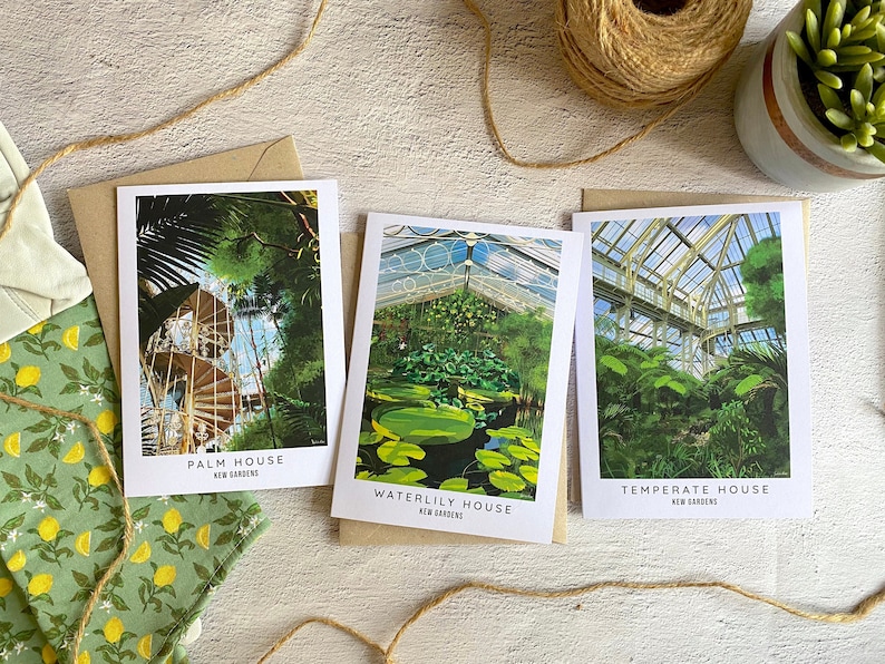 Peut inclure: Trois cartes postales repr&eacute;sentant des images de la Palm House, de la Waterlily House et de la Temperate House des Jardins de Kew. Chaque carte postale a une bordure blanche et porte le nom de la maison et "Kew Gardens" en texte noir.