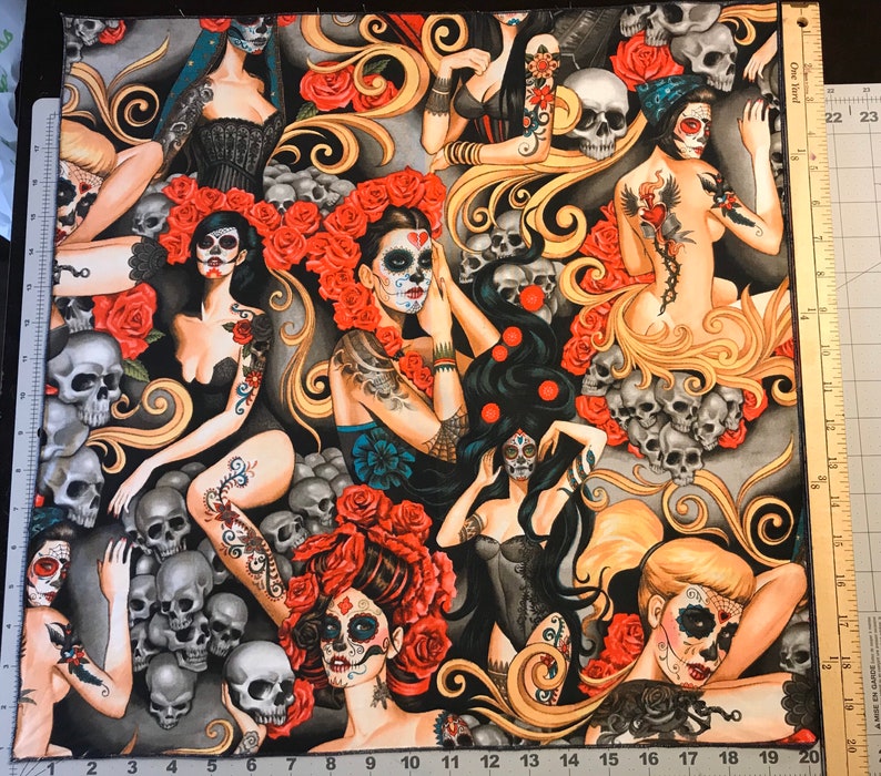 May include: A colorful fabric with a repeating pattern of women with sugar skulls and floral accents. The background is gray with swirls and skulls.