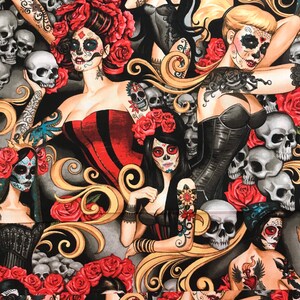 May include: A black fabric with a repeating pattern of sugar skulls, roses, and ornate swirls. The sugar skulls are decorated with colorful flowers and have black eyes. The roses are red and have green leaves. The swirls are gold and are arranged in a decorative pattern.